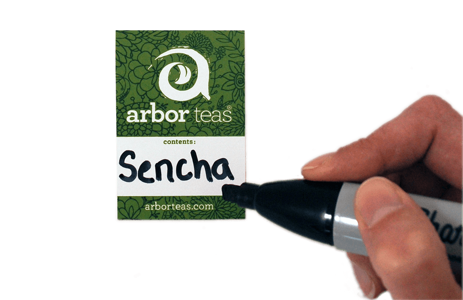 Hand holding a marker writing on an Arbor Teas Label