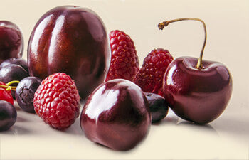 Assorted berries including cherries and raspberries on a light background