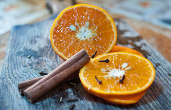 Sliced oranges with cinnamon sticks on a wooden surface