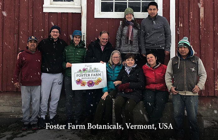 Group of people standing in front of a red barn holding a sign for Foster Farm Botanicals, Vermont, USA.