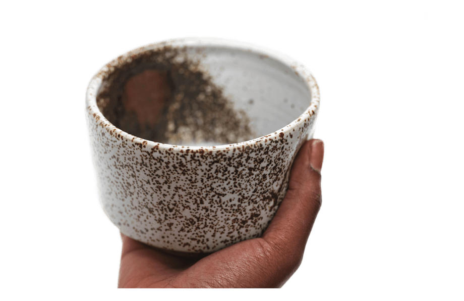 Hand holding a ceramic matcha bowl with speckled design