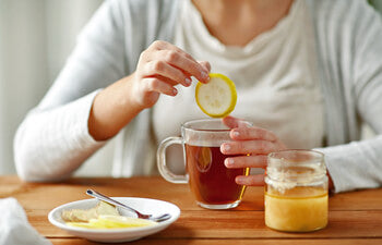 Person adding a lemon slice to a cup of tea