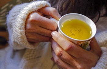Person holding a cup of tea in two hands
