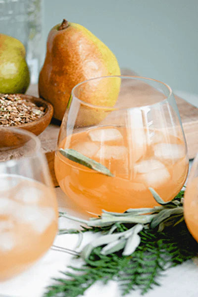 Glass filled with Tipsy Partridge cocktail with pear in background
