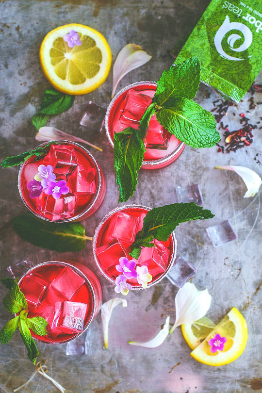 Four glasses of Spiked Hibiscus Iced Tea with mint leaves