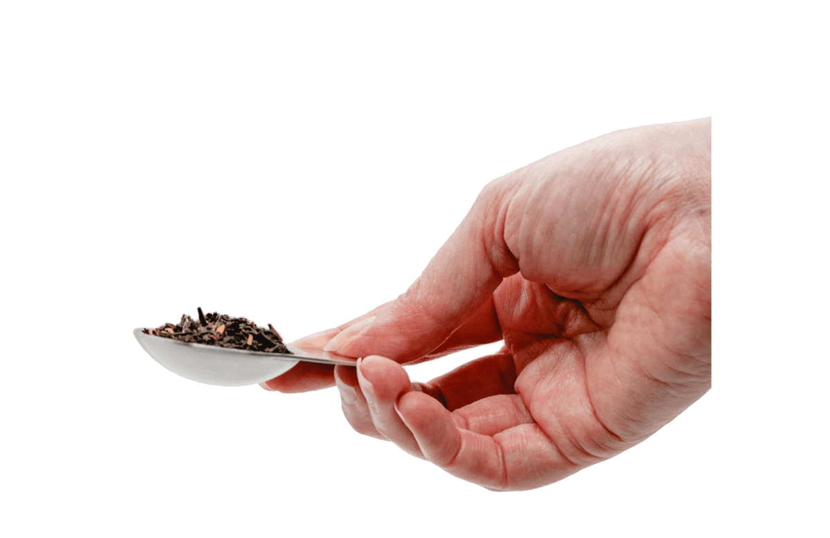 Hand holding a spoon with tea leaves 