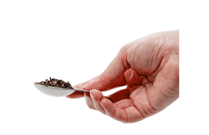 Hand holding a spoon with tea leaves 