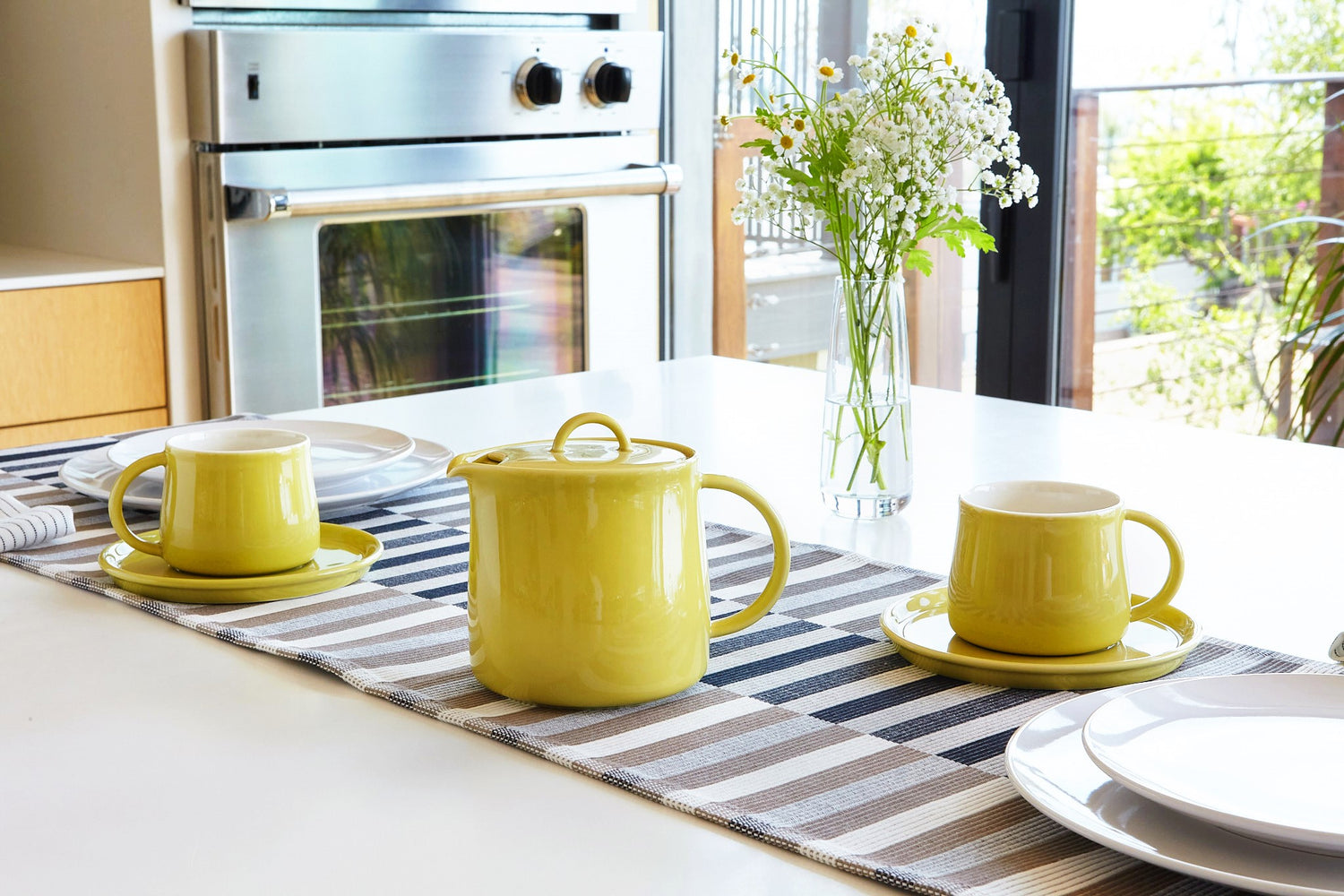 Limoncello D'Anjou teapot and mugs on a striped table runner with a kitchen background