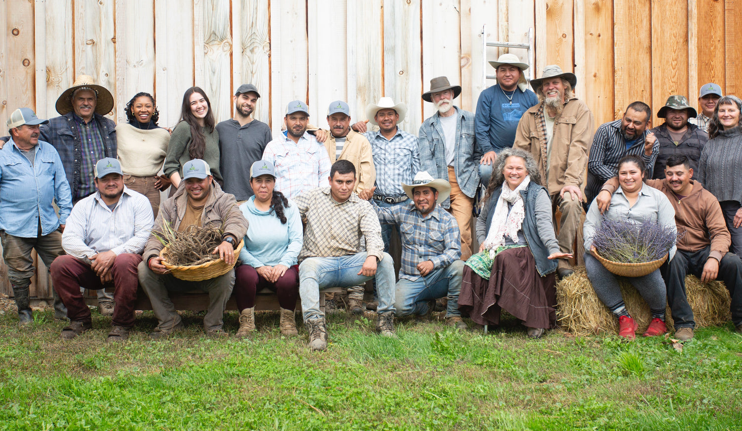 Oshala Farm family and crew posing outdoors with a wooden fence in the background