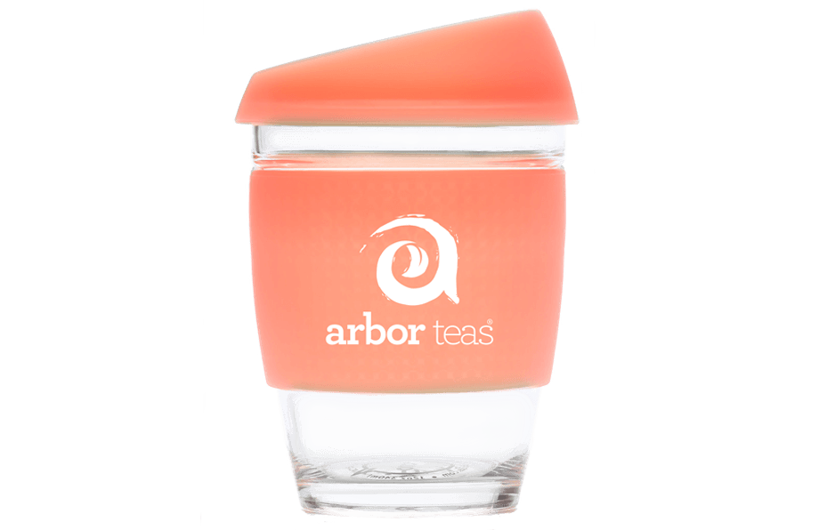 Clear glass tumbler with a coral-colored sleeve featuring the 'arbor teas' logo 