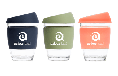 Three reusable cups with different colored lids and 'arbor teas' branding