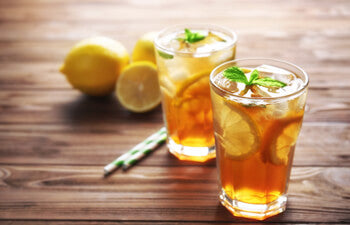 Two glasses of iced tea with lemon slices on a wooden surface