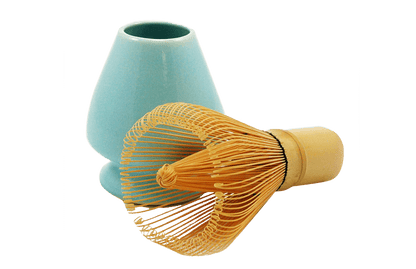 Bamboo whisk laying next to a Turquoise ceramic matcha stand